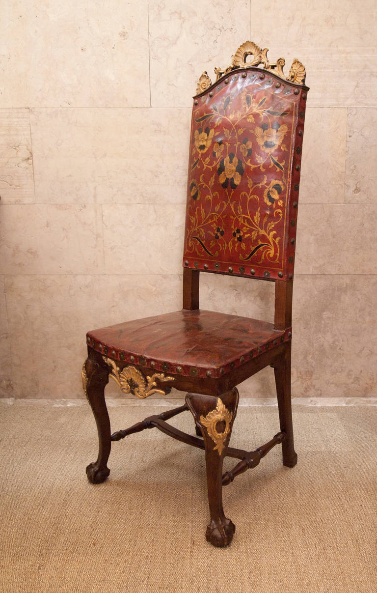 A pair of Dom João V chairs. Carved and parcel-gilt walnut, seat and back upholstered in painted leather.
Portugal, 18th century.

D. João V period (1707-1750) furniture. Greatly influenced by English furniture from the late 17th century, due to