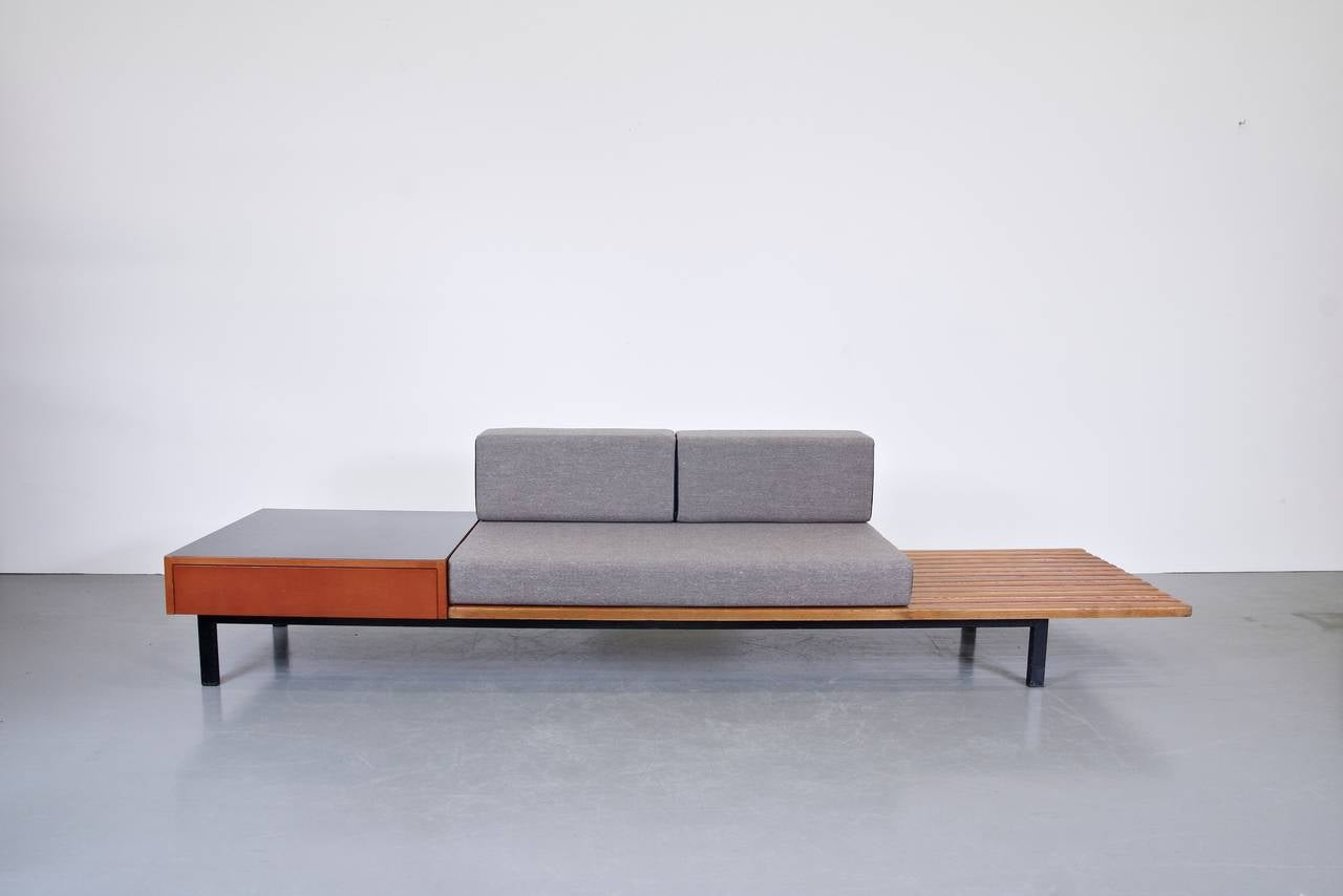 Amazing bench with integrated side table and drawer, from Cite Cansado, Mauritania, designed by Charlotte Perriand.

The bench is made from beautiful oak on a black metal base. The drawer has a black laminated top. The cushions are reproductions,