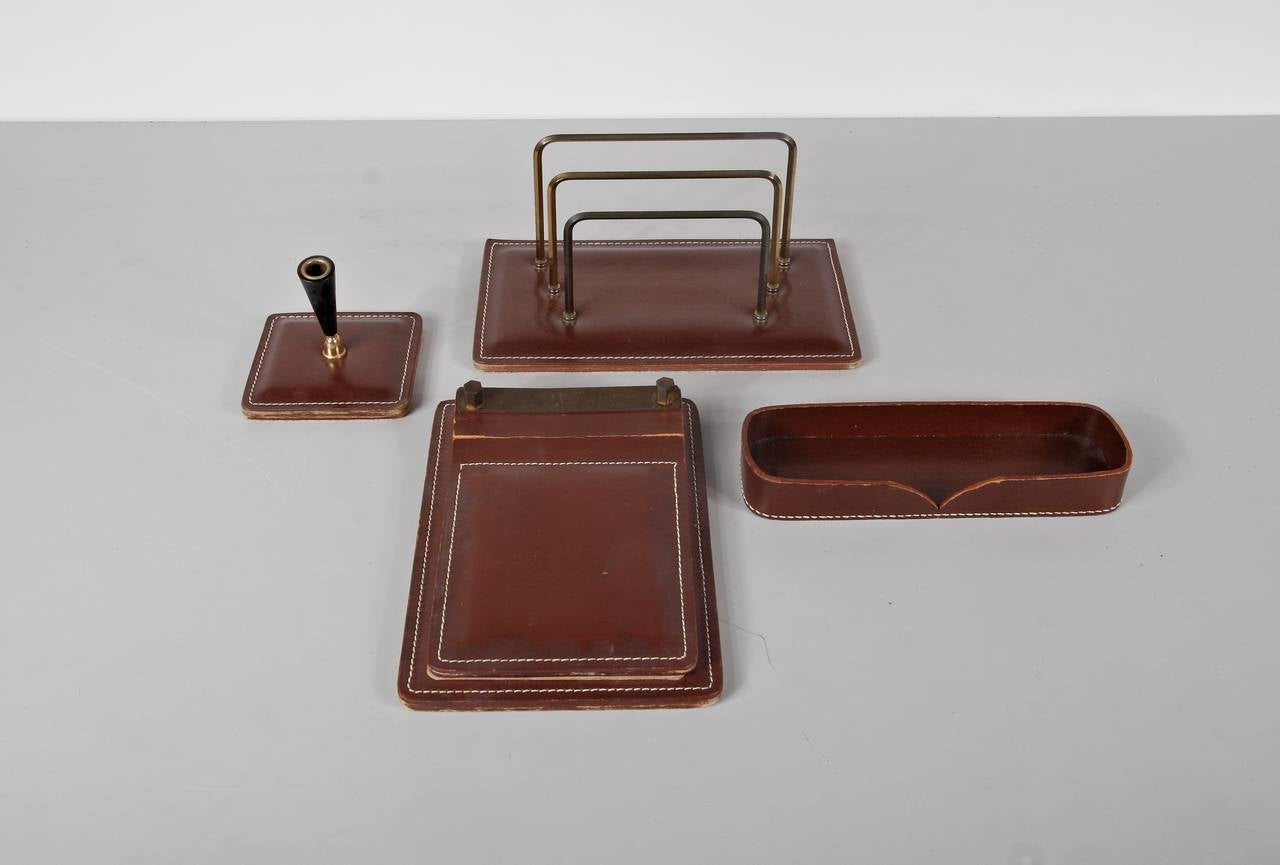 Office set design attributed to Jacques Adnet.
Manufactured in France, circa 1950.
All in leather with brass details.

In good original condition, with minor wear consistent with age and use, preserving a beautiful patina.