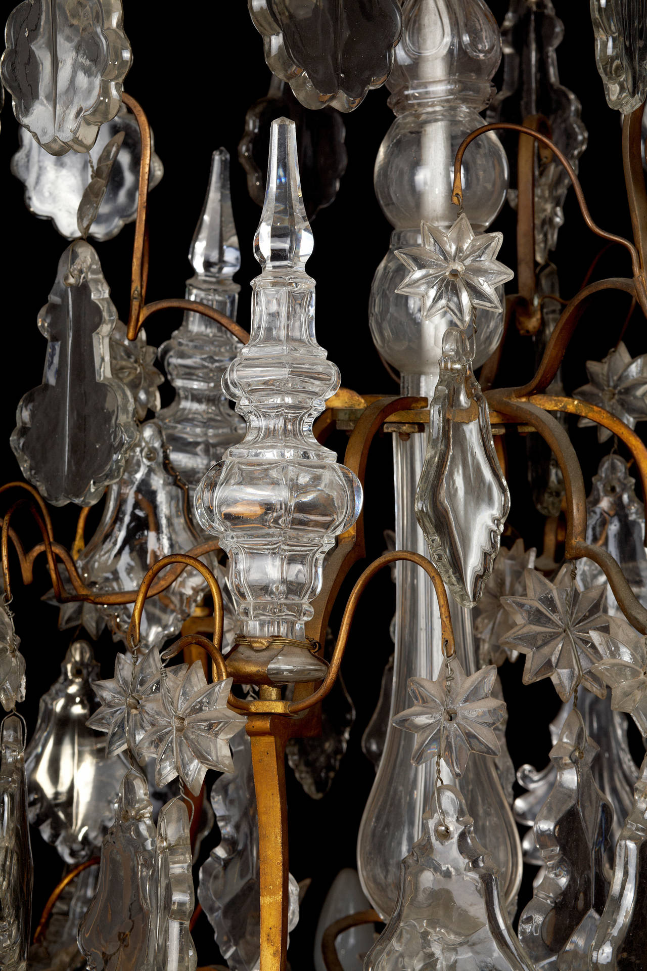 An exquisite 18th century French bronze and crystal chandelier. The birdcage frame is profusely hung with cut crystal plaques, unusual shell plaques and star rosettes. The nine arms of light are interjected with beautifully large cut-glass finials