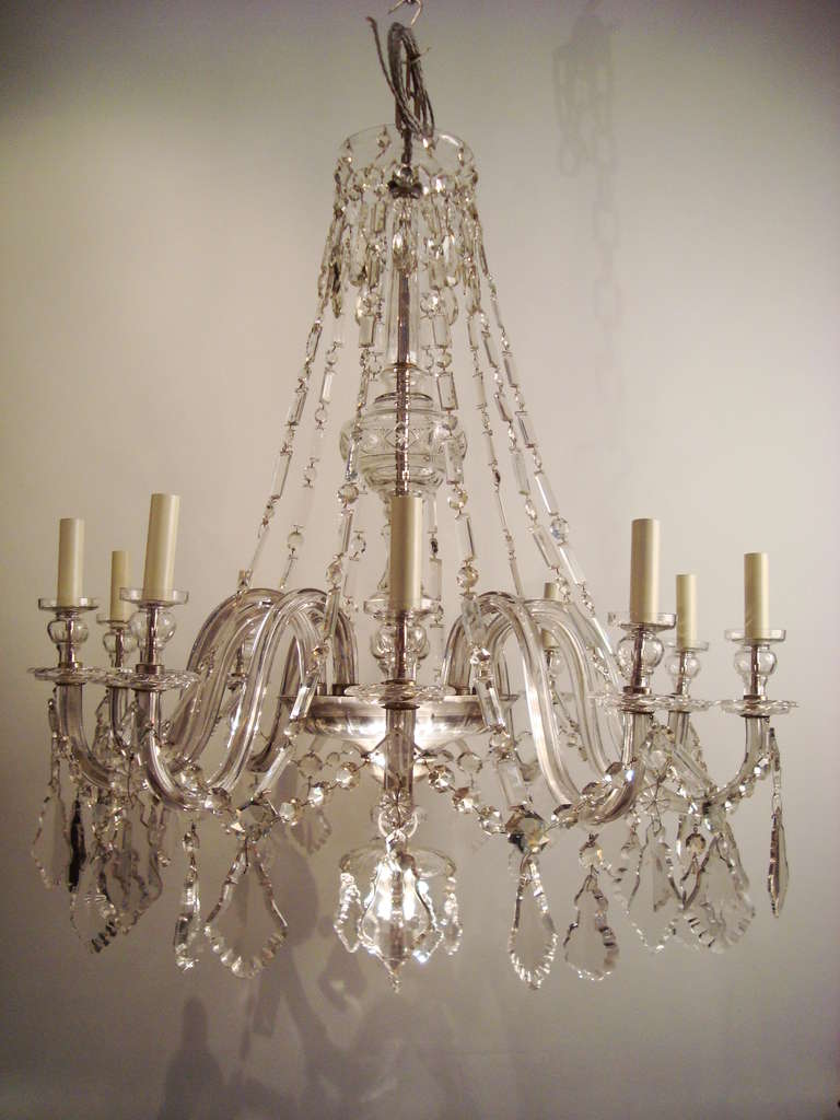 A large ten arm glass and crystal chandelier, in the manner of Baccarat, the baluster shaped cut glass stem projecting ten hollow glass arms, with glass drip pans and nozzles, adorned with chain made of faceted rectangular crystal prism and