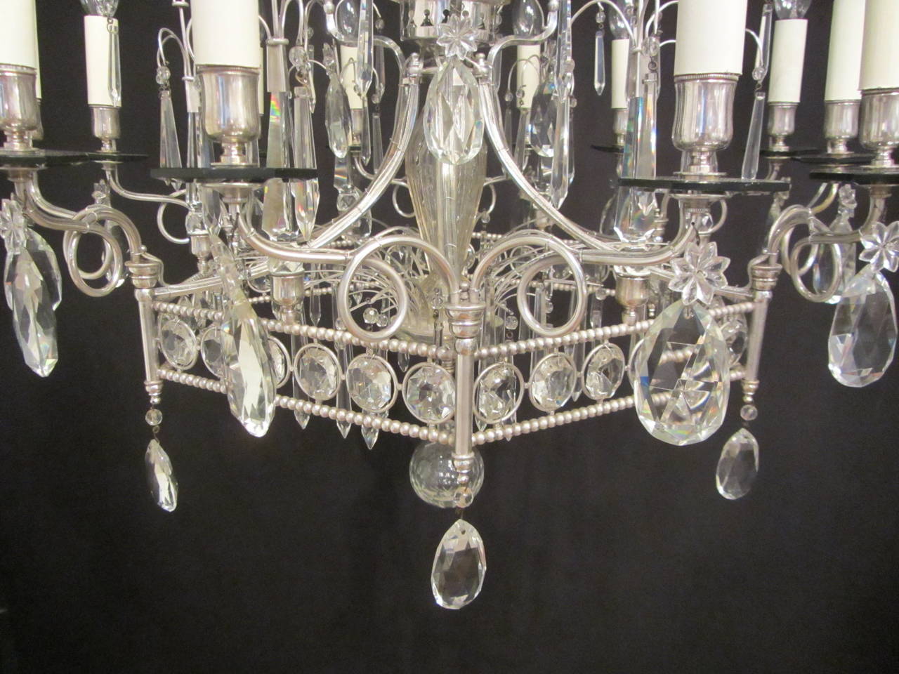 A twelve-armed, silver plated brass and crystal pentagonal chandelier of unusual design, with a fountain like structure and cut-glass drops and buttons.