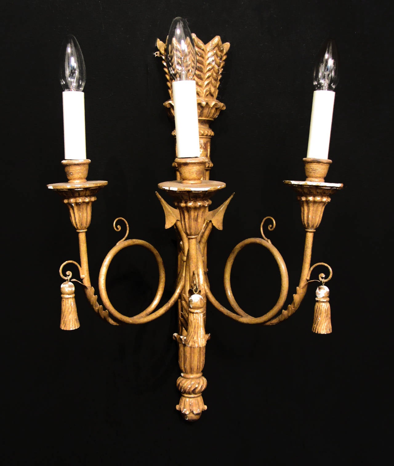 A set of four, large, richly carved giltwood, three-arm Empire style wall appliqués. The decorative scrolling design in the form of a quiver with three looped branches supporting the candle holders. Can be sold in pairs. Professionally wired for