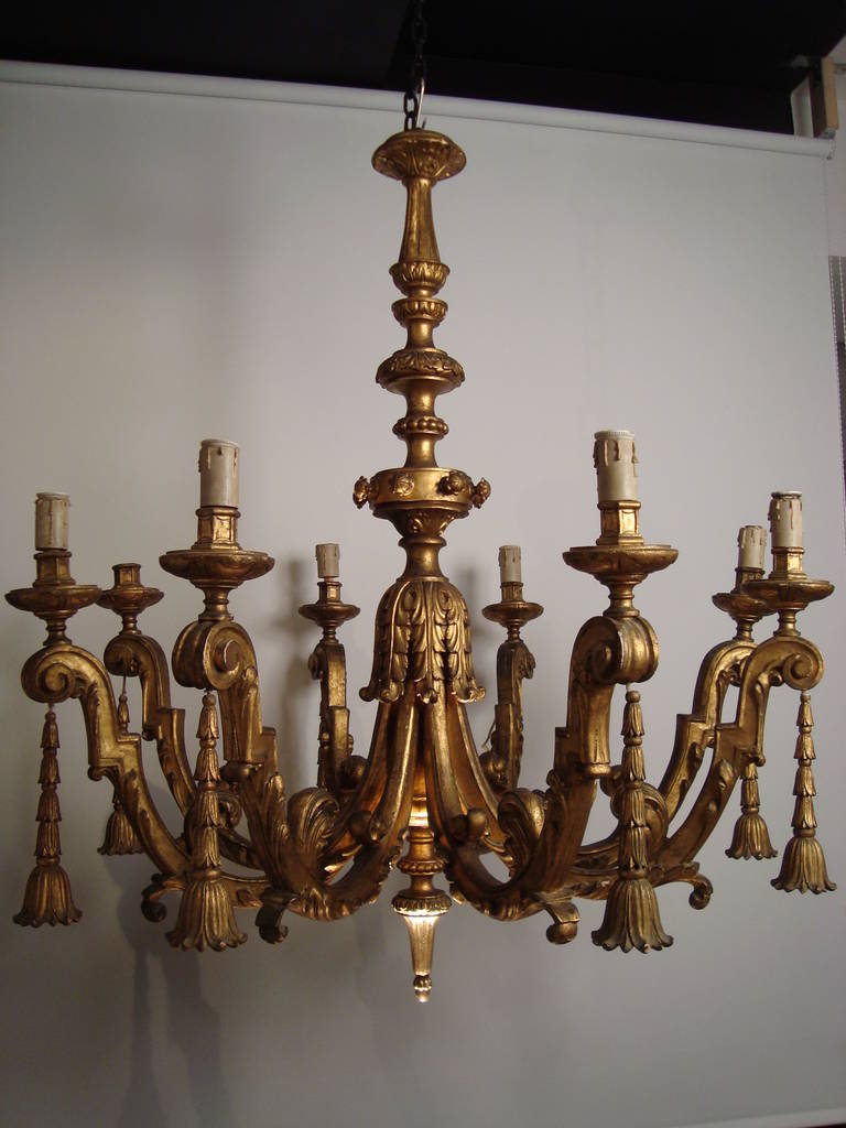An impressive and large carved giltwood Italian 19th century chandelier, the elegantly carved stem projecting eight arms of light, each hung with a carved giltwood stylized stiff leaves element, Italian, circa 1880.