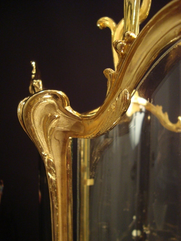 A large four-light Louis XV style gilded bronze lantern, the elegantly shaped frame, gold plated with 24-carats gold, hand finished and finely chiseled, forming a drum, supported by four acanthus designed struts, terminated by four grapes and leaves