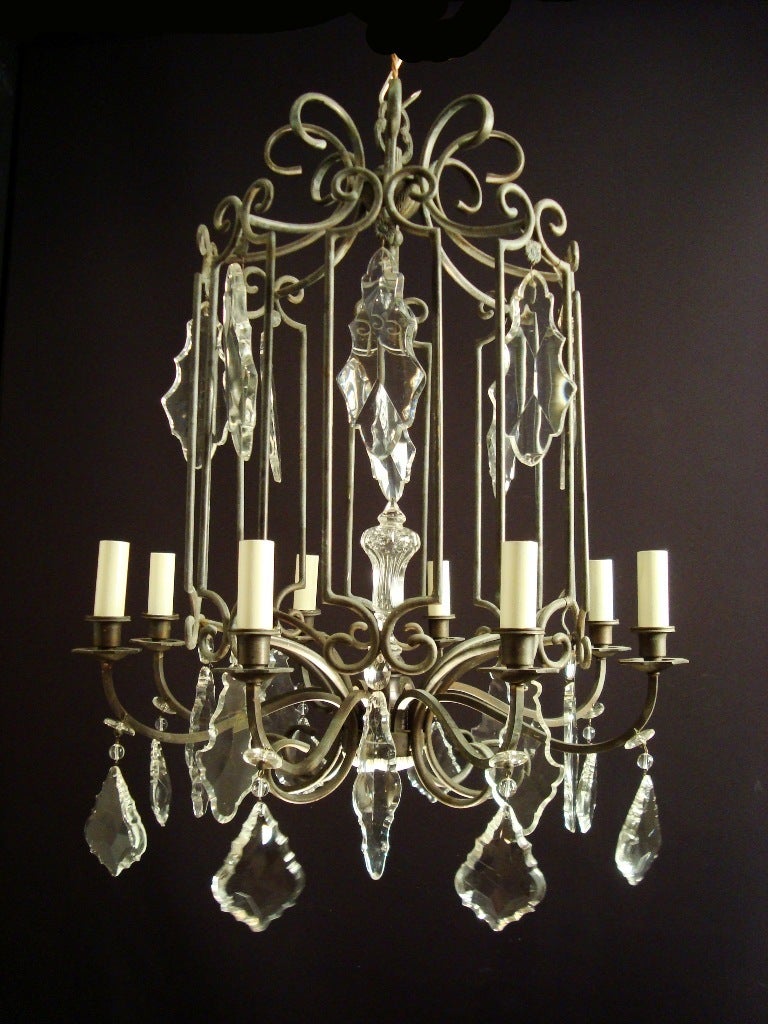A most unusual black patinated brass and crystal rotunda shaped chandelier, the design of chinoiserie influence, projecting eight arms, hung with large crystal plaques and centered by a very nice cut-glass finial, French, circa 1920 

Measures: