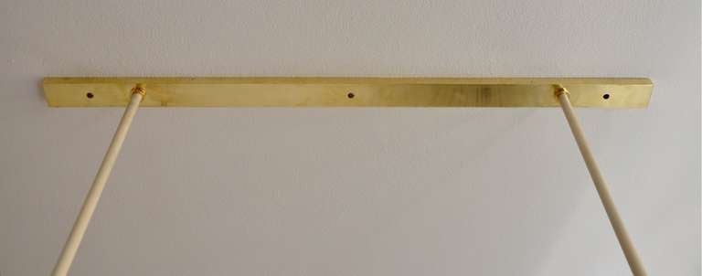 An elegant 1950s ceiling lamp manufactured of brass and painted metal. The lamp would suit well over a large rectangular dining table or any space requiring abundant central lighting.
Each shade carries two sockets, one illuminate the ceiling and