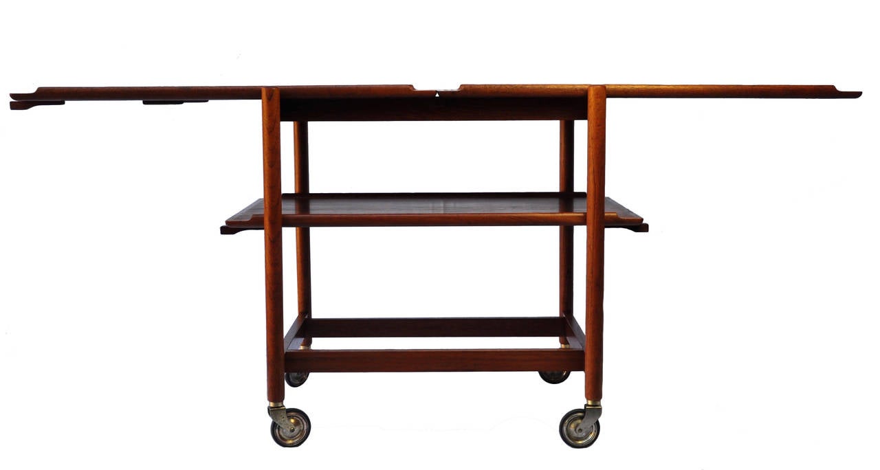 A triplex bar cart in richly aged teak with plated metal and rubber wheels. Either of the bottom platters can be removed and added alongside the fixed top platter so as to expand the service area the bottom platters can also be used as portable