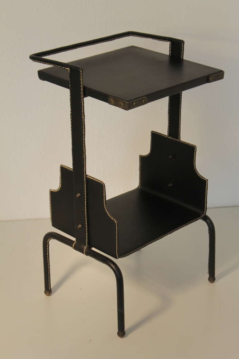Jacques Adnet brass and stitched black leather. Metal covered by black leather with brass details. The trays are covered with black vinyl.
