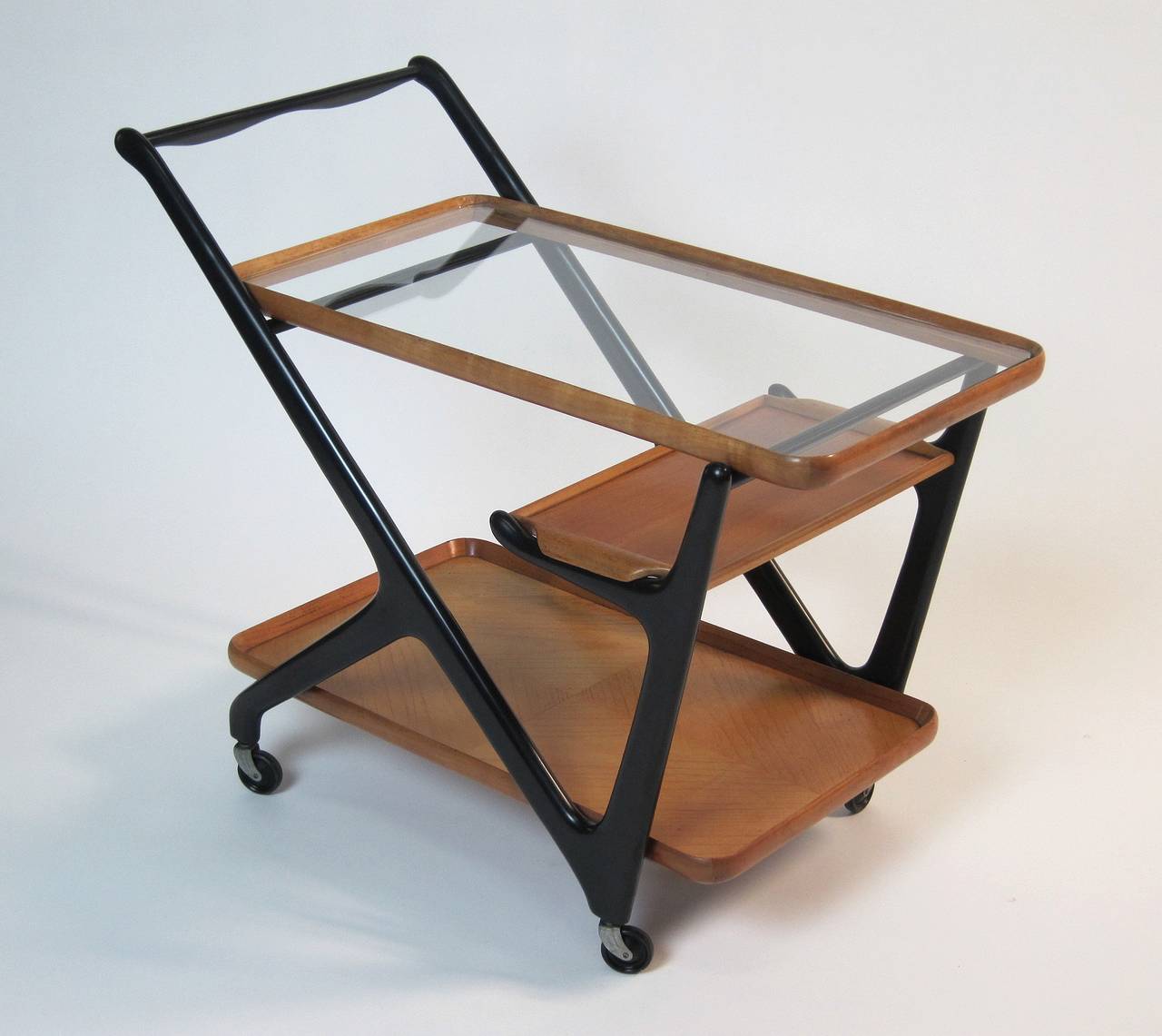 Manufactured in Italy 1950s, this organic wooden trolley includes a small serving tray, top with new glass (original existing).