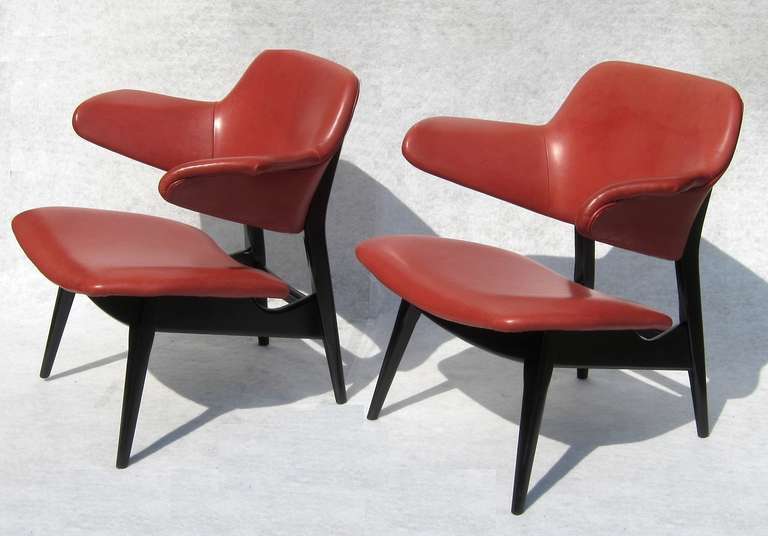 Sculptural and comfortable chairs, covered with red leather, black lacquered wooden frame