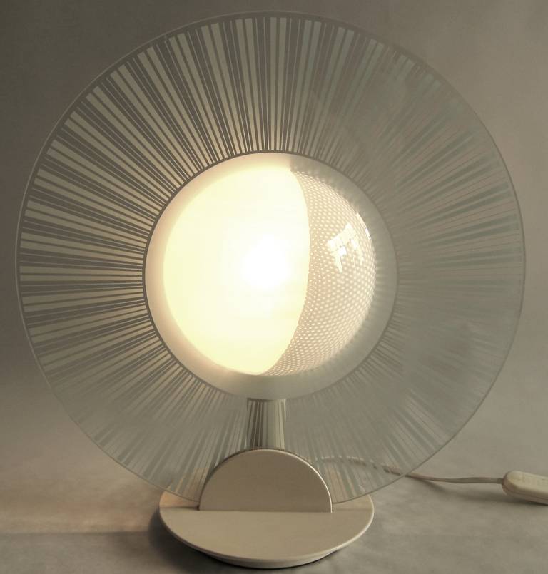 Fascinating lamp composed of a glass disc with a hemispherical convexity, where a rotating hemispherical perforated metal sheet eclipses the light.