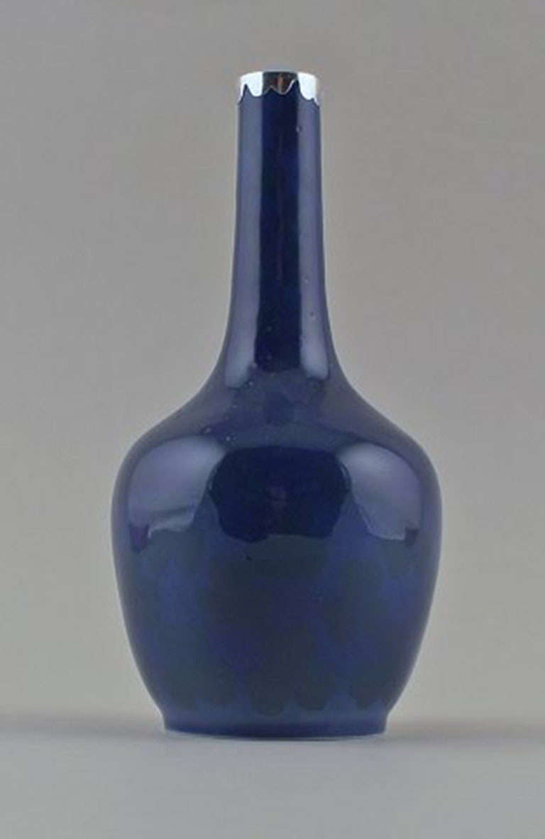 Royal Copenhagen Art Nouveau vase with silver mounting, decorated with shamrocks in beautiful royalblue glaze. Rare vase. Measures: 17.5 cm high. In good condition. Stamped.