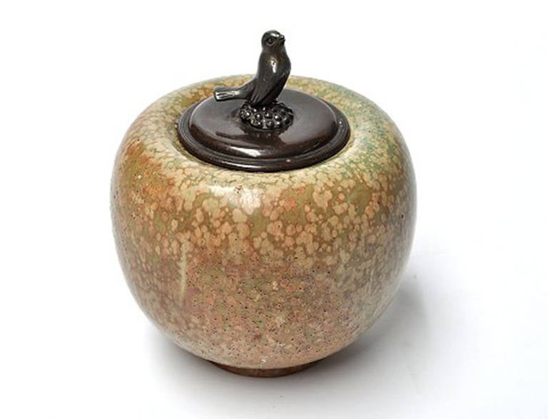 Carl Halier and Georg Thylstrup for Royal Copenhagen. Spherical vase in stoneware, decorated with speckled glaze. Stamped 92/4. Lid of patinated bronze lid knob in tin in the form of a bird by Georg Thylstrup. 
Heights 17 cm. In good condition.