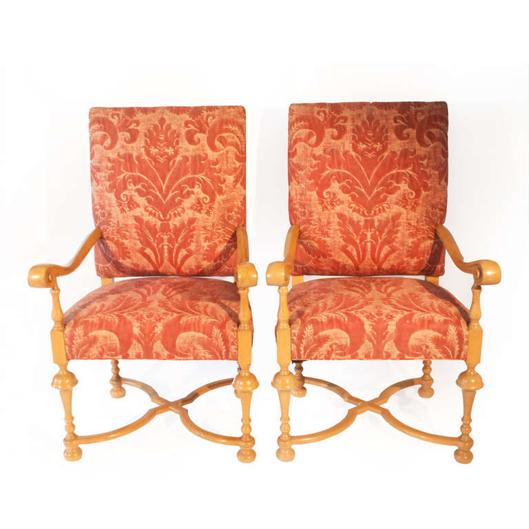 Two light-stained Armchairs made in the 20th century in William and Mary 
style.  The rectangular backs and seats are upholstered  in Claremont  Fortuny rose cotton damask.  The chairs have outscrolled arms on turned tapered legs joined with cross