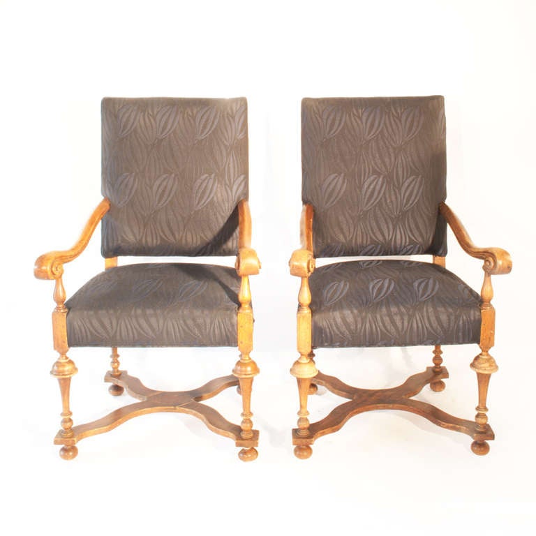 Two light-stained Armchairs made in the 20th century in William and Mary 
style.  The rectangular backs and seats are upholstered in indigo-coloured silk. The chairs have outscrolled arms on turned tapered legs joined with cross stretchers and on