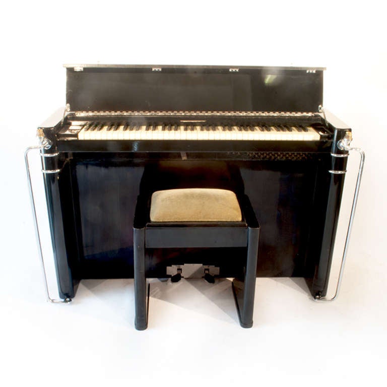 An Art Deco (possibly Eavestaff) ebonised and chrome-mounted piano, 
impressed number 1460 the hinged keyboard cover flanked by round ends, mounted with chrome handles and electric light fittings. With matching piano stool.

85 cm high
139 cm