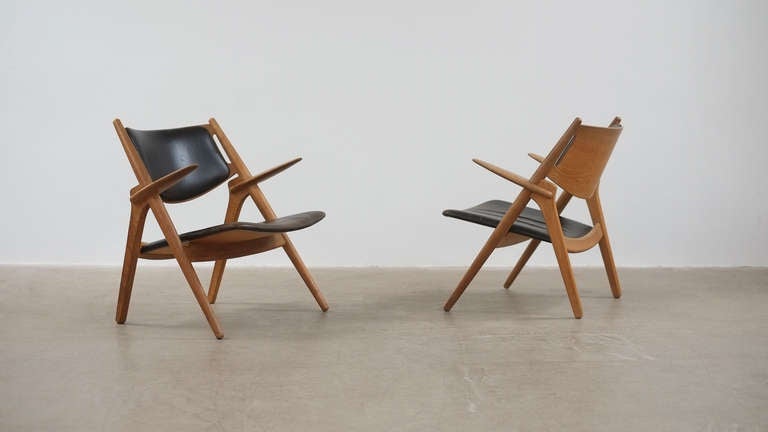 Amazing and rare pair of first production CH28 or Sawback lounge chairs designed by Hans Wegner for Carl Hansen, Denmark. These are a super fine pair of early chairs in oak with original black leather with wonderful patina. Truly staggering pair of
