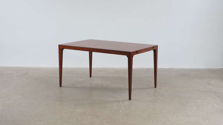 Amazing dining table in solid rosewood and rosewood veneers designed by Kai Winding for Poul Hundevad, Denmark. Super elegant design and ultra high quality table with unique system for using the two extension leaves which can be stowed underneath