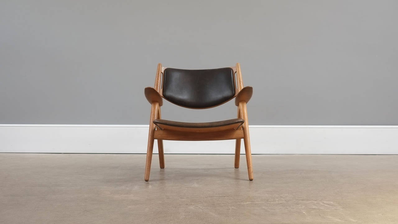 Amazing and rare first production CH28 or Sawback lounge chair designed by Hans Wegner for Carl Hansen, Denmark. Early chair in oak with original black leather with wonderful patina. Perfect example.