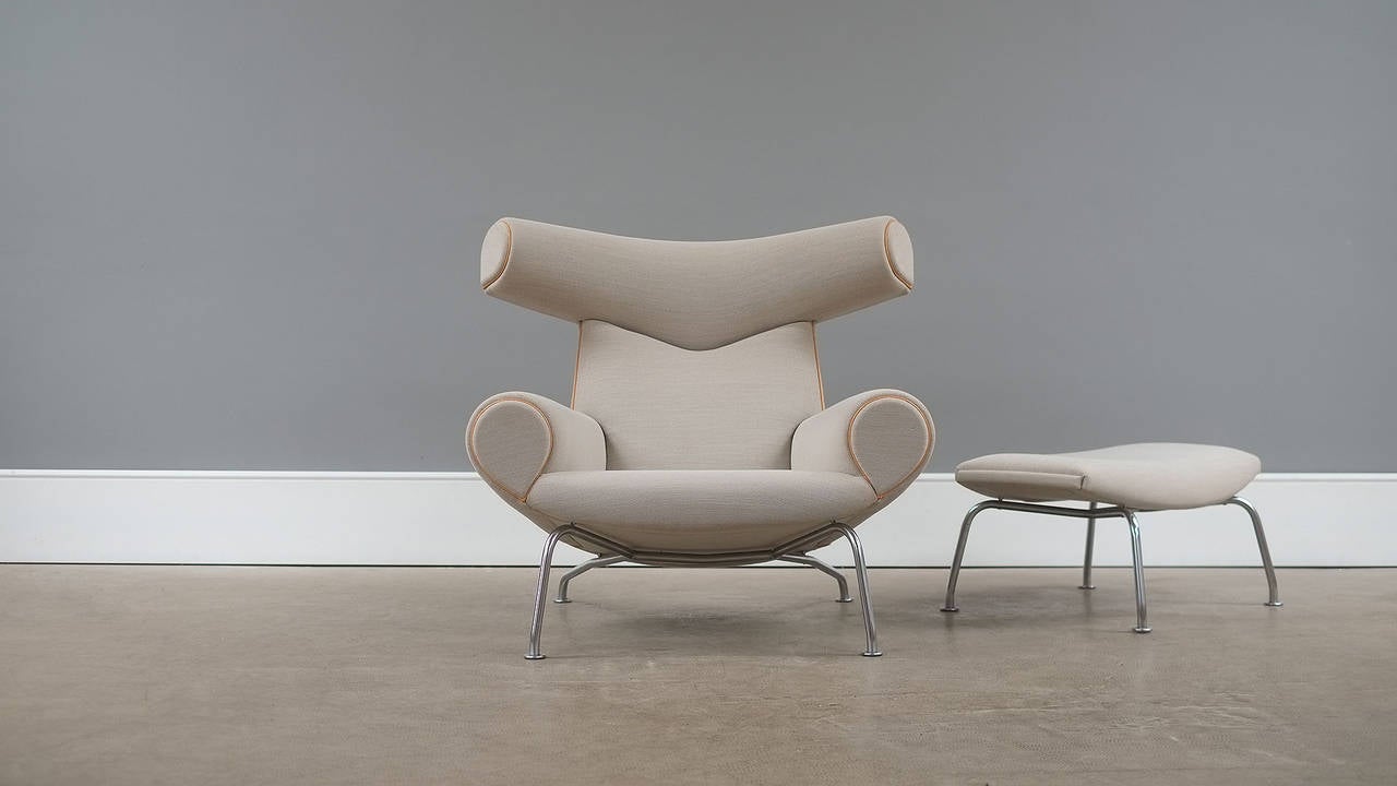 Amazing and super sought after vintage Ox chair and Ottoman designed by Hans Wegner for AP Stolen, Denmark. Wonderful example of this seldom seen and iconic Wegner chair with recent re-upholstery in ecru fabric with natural leather piping.