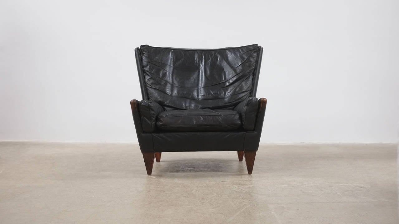 Monumental V11 Lounge chair in superb black leather with rosewood pyramid legs designed by Illum Wikkelso for cabinet maker Holger Christiansen, Denmark. Beautiful and rare chair.