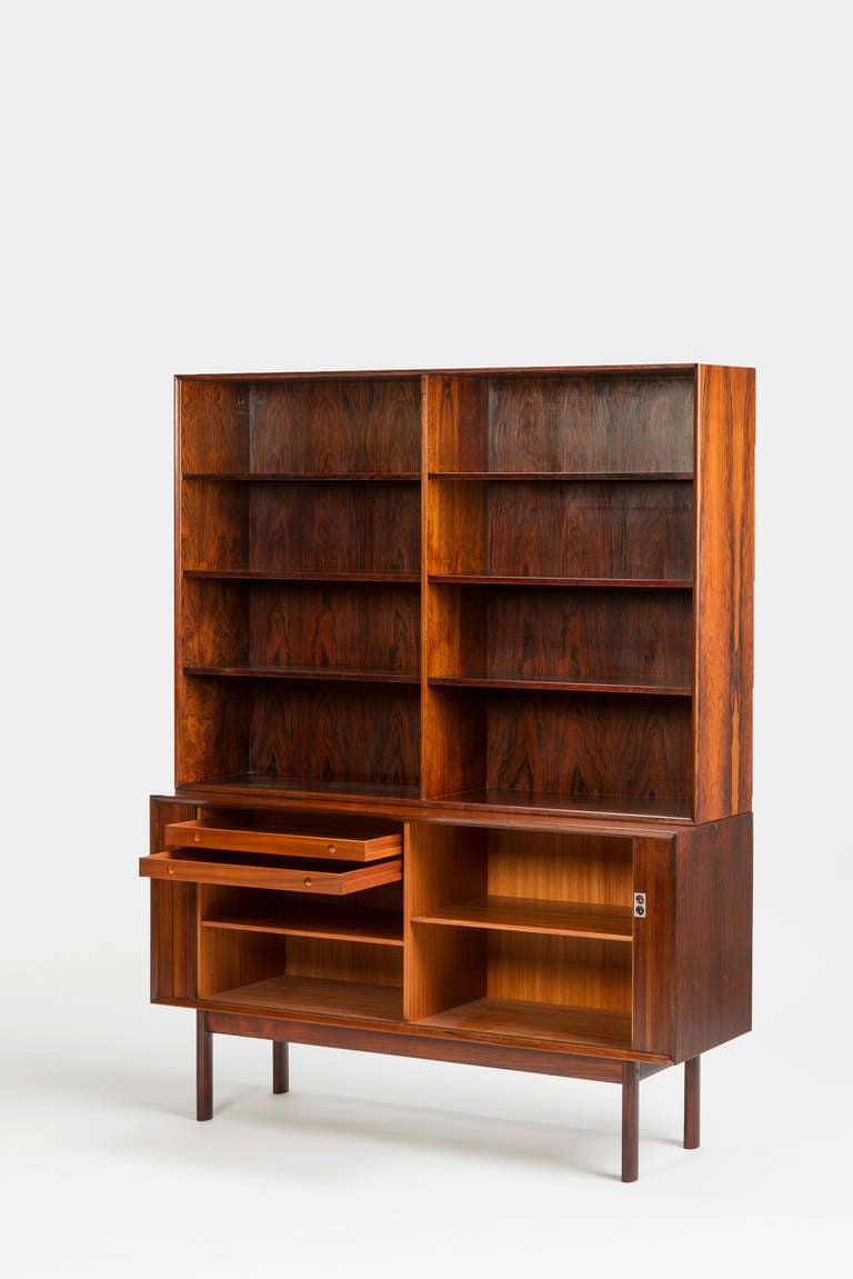 Stunning rosewood bookcase designed by Arne Vodder, made in Denmark by Sibast Furniture. The sideboard underneath, which is not fixed to the upper cupboard, is composed of a mahogany interior with two small drawers. The exterior, with it's sliding