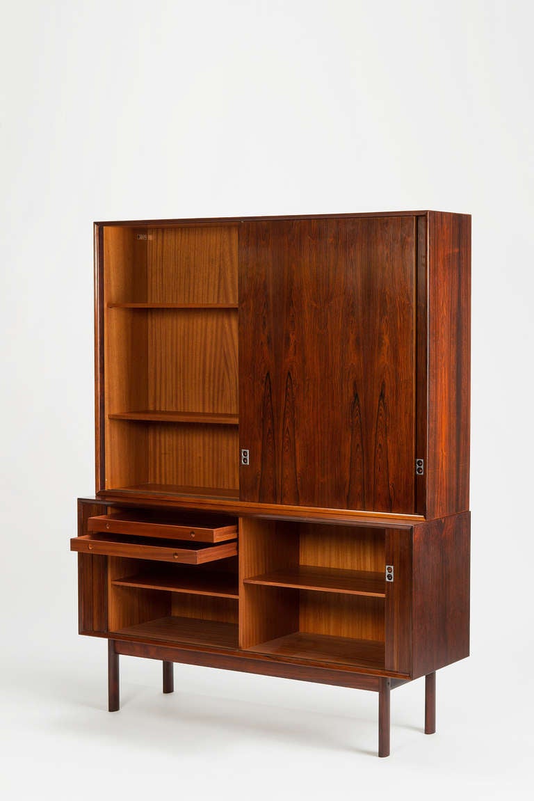 Stunning rosewood bookcase designed by Arne Vodder, made in Denmark by Sibast Furniture. The sideboard underneath, which is not fixed on the upper cupboard is composed of a mahogany interior with two small drawers. The exterior with its sliding