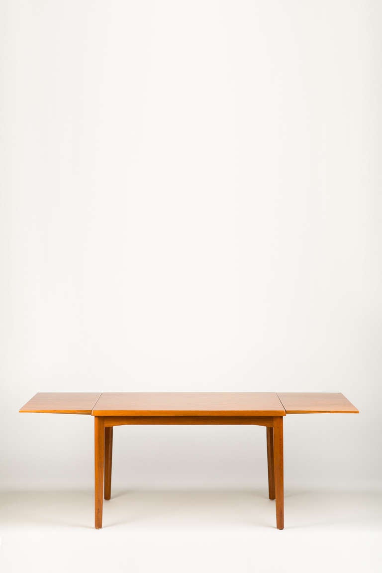 Very nice proportioned dining table in teak wood by Henning Kjaernulf, manufactured by Vejle Stole Møbelfabrik, Denmark. Features Two extension leaves hidden under the tabletop which lifts to allow the leaves to slide out and extend the length of