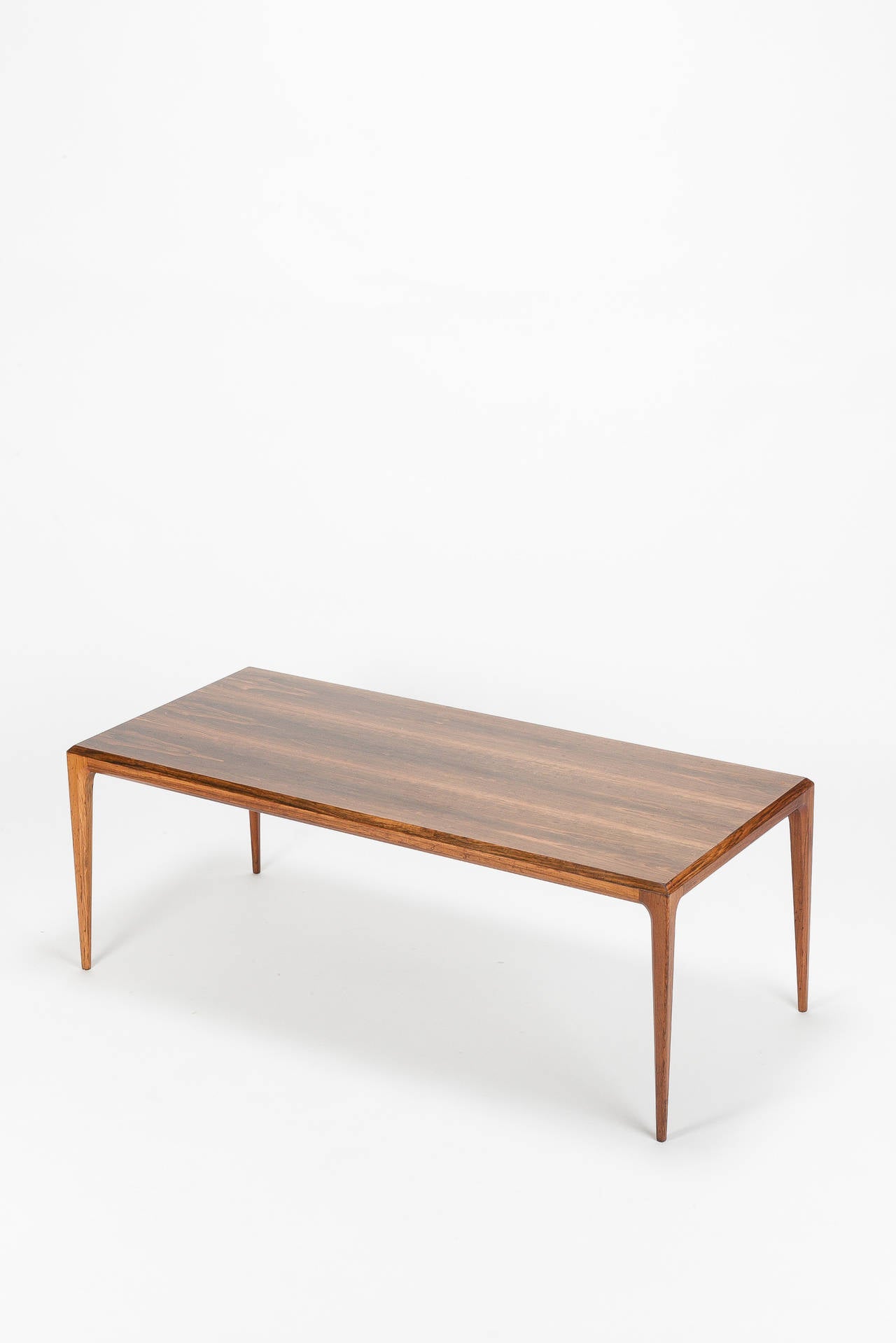 Tavolino danese progettato da Johannes Andersen per CFC Silkeborg in Danimarca, anni '60. Realizzato in un bellissimo legno di palissandro venato, ha una forma molto unica ed elegante con bordi inclinati e gambe a forma di cono.