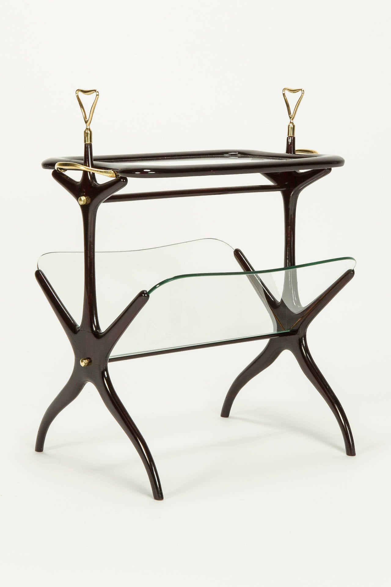 Sophisticated side table by Cesare Lacca, Italy, 1950s. The frame is made of lacquered mahogany; the top tray is removable to serve drinks with brass handles. Underneath are glass shelves for magazines and news.