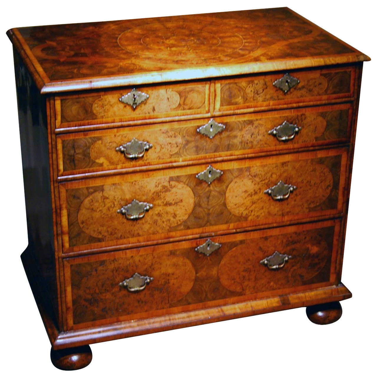 A very good William and Mary period oyster veneered olivewood chest of drawers, the top with a four lobed central reserve of oyster veneers crossbanded with walnut and a semi ovulo moulded edge, the sides with concave cornered bandings and central