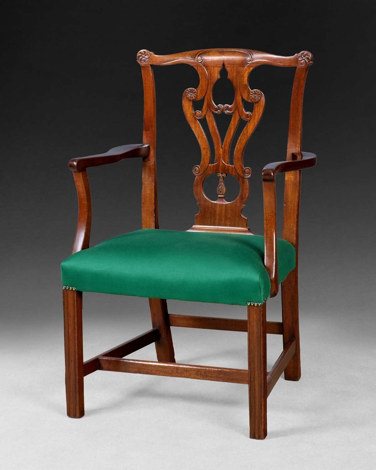 A good Chippendale period mahogany elbow chair, the delicately carved interlaced back splat flanked by outswept arms and the whole raised on square moulded legs.