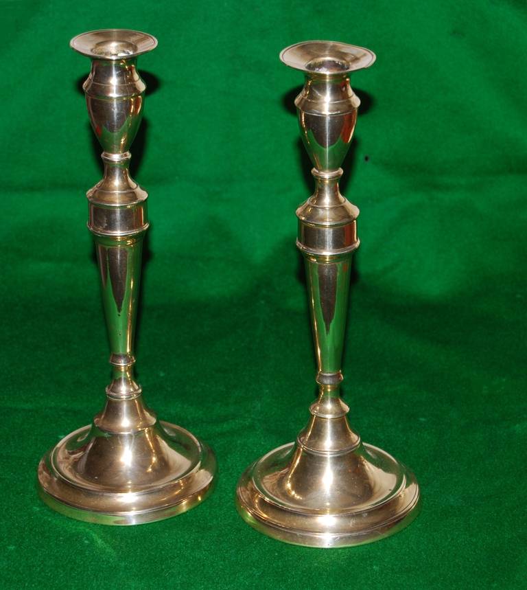 A good pair of George III period brass candlesticks, the turned drip pans over vase shaped holders and tapered columns on stepped circular bases.