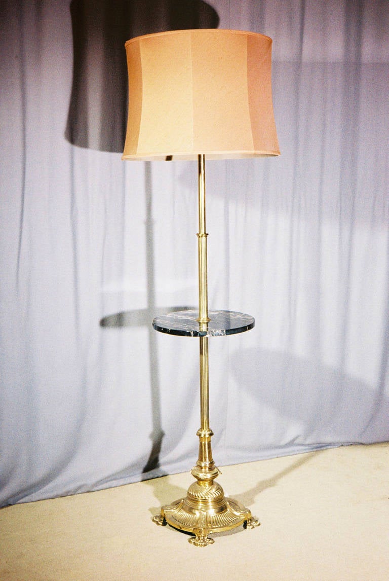 Mid-19th century brass adjustable standard lamp, the telescopic sections joined at a circular marble table platform, the weighted base with a reeded stem and reeded details to the four lobed platform. This has been converted to electricity from oil.