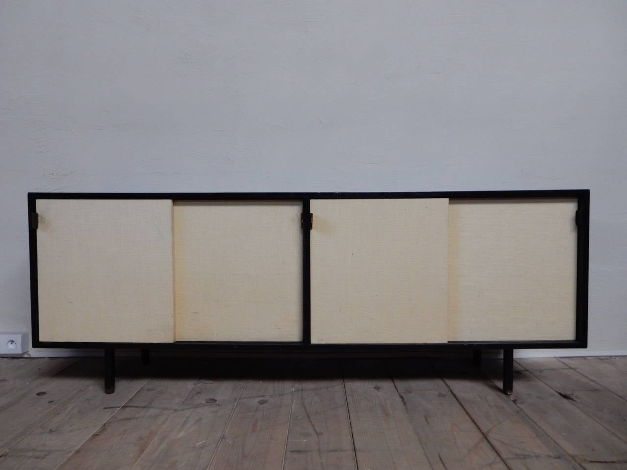 A very nice lare sideboard from Florence Knoll edited and signed by Knoll Internatonnal circa 1960
this model  is with 4 sliding doors covered by new parchment paper and with 4 leather pulls(one has been changed and is new)
the black lacquered