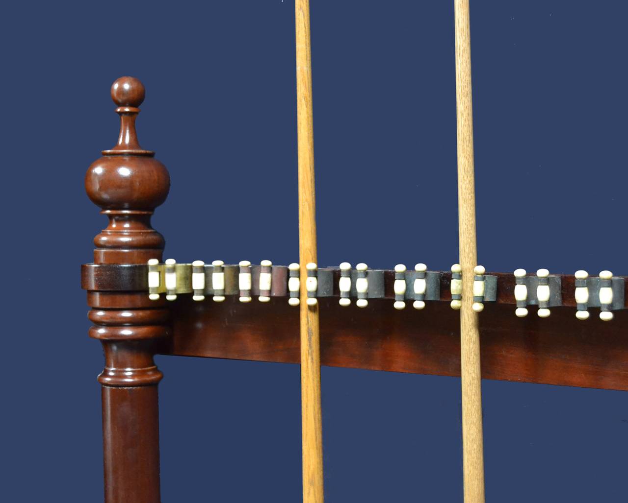 A mahogany framed Billiard - Snooker cue rack with upright columns topped with decorative finials, fitted with original bone clips and able to hold 18 cues.