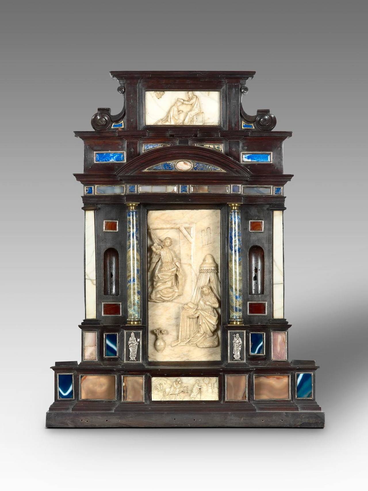 Beautiful portable altar.
Rome. Early 17th century.
Ebony wood, marble, alabaster, hard stones and silver.
73 cm. (high)x 56.5 (width) x 11.5 cm (deep).

Alabaster reliefs: 
- The principal scene represents The Annunciation (measures: 31,5 x