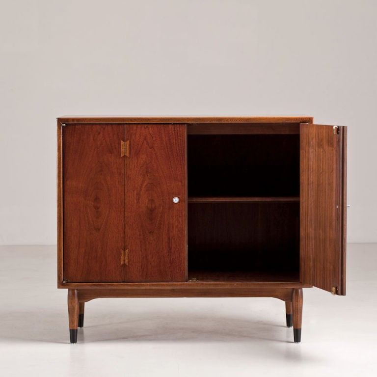 Single 1950s wooden end/side cabinet with nickel sphere handles adorning a pair of doors which have been inlaid and designed to look like they are concertinaed. The cabinet is set on tapered legs with ebonized caps to the feet, 1950s.