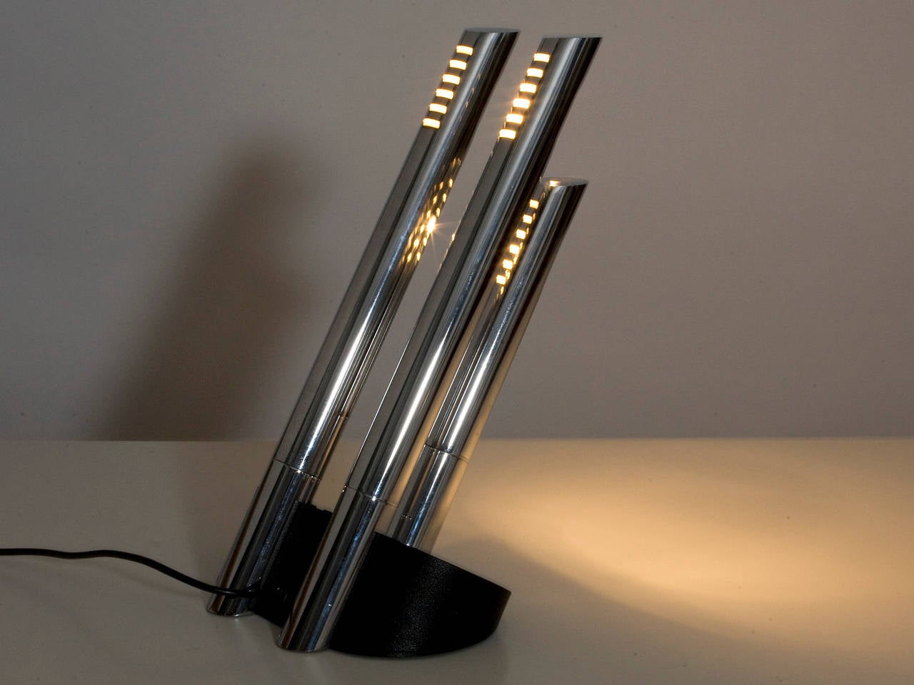 Cast metal base. 4 angled chromed tubes with orientable diffusers. Front and back tubes can be lit independently.