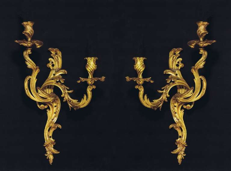 Each with asymmetric form, the acanthus and C-scroll-cast backplate
issuing two scrolled foliate branches with pierced rocaille, terminating
in pierced asymmetrical drip-pans and foliate-cast nozzles, the base with trailing foliage.