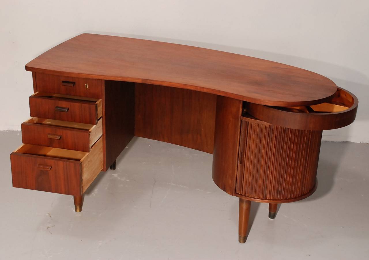 Beautiful desk from the danish designer Kai Kristiansen. There is a small bar on the right side, three drawers on your left and a hidden drawer above the bar for small items. There is no key.