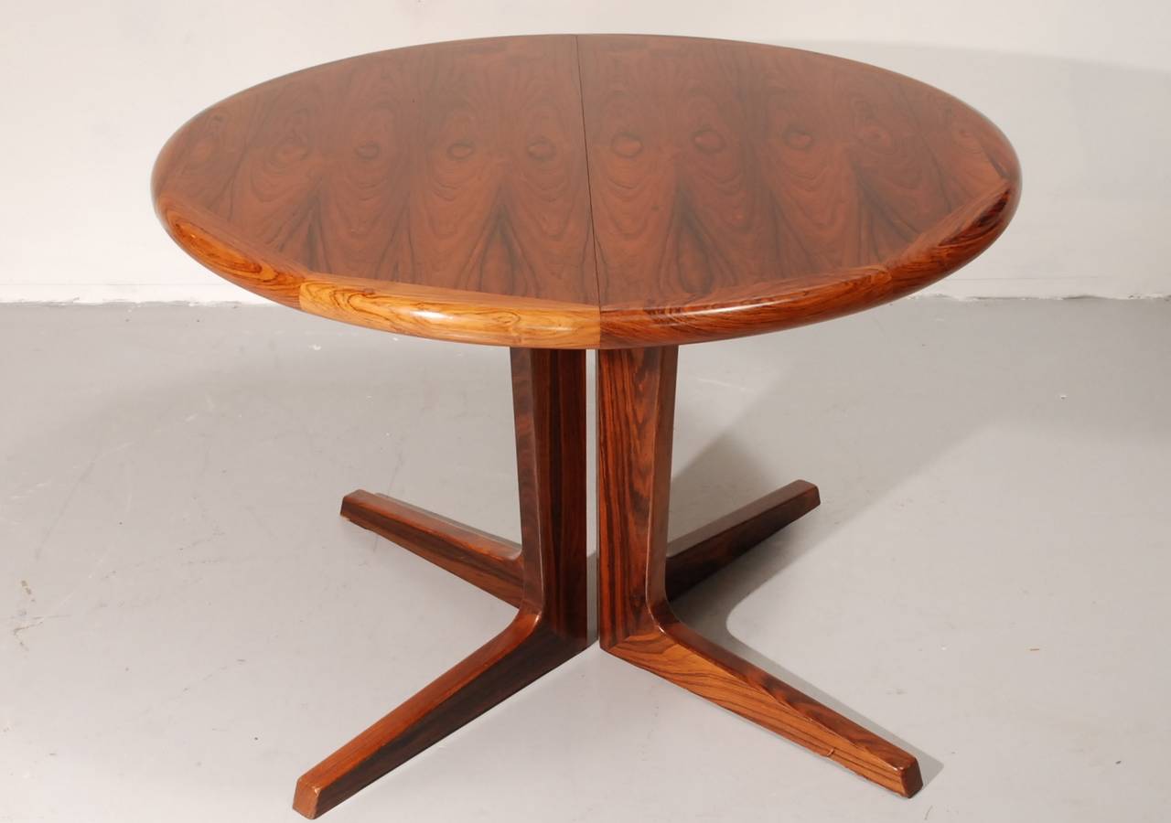 Danish dining table from K.S. Mobler. This round table is made of a veneered middle with solid edges. The feet are of solid palisander as well. The extensions are also veneered with solid sides.  The price includes delivery to the US.