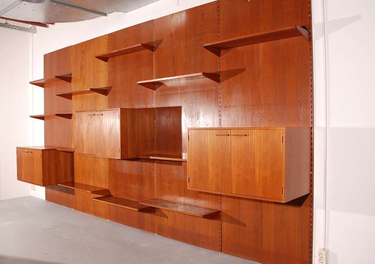 Gigantic wall system from Kai Kristiansen, made in Denmark. 
This system is flexible and has 11 shelves and three hanging cabinets.
We have more element in stock, so it can be delivered in smaller parts.
All is made of solid teak and teak veneer.