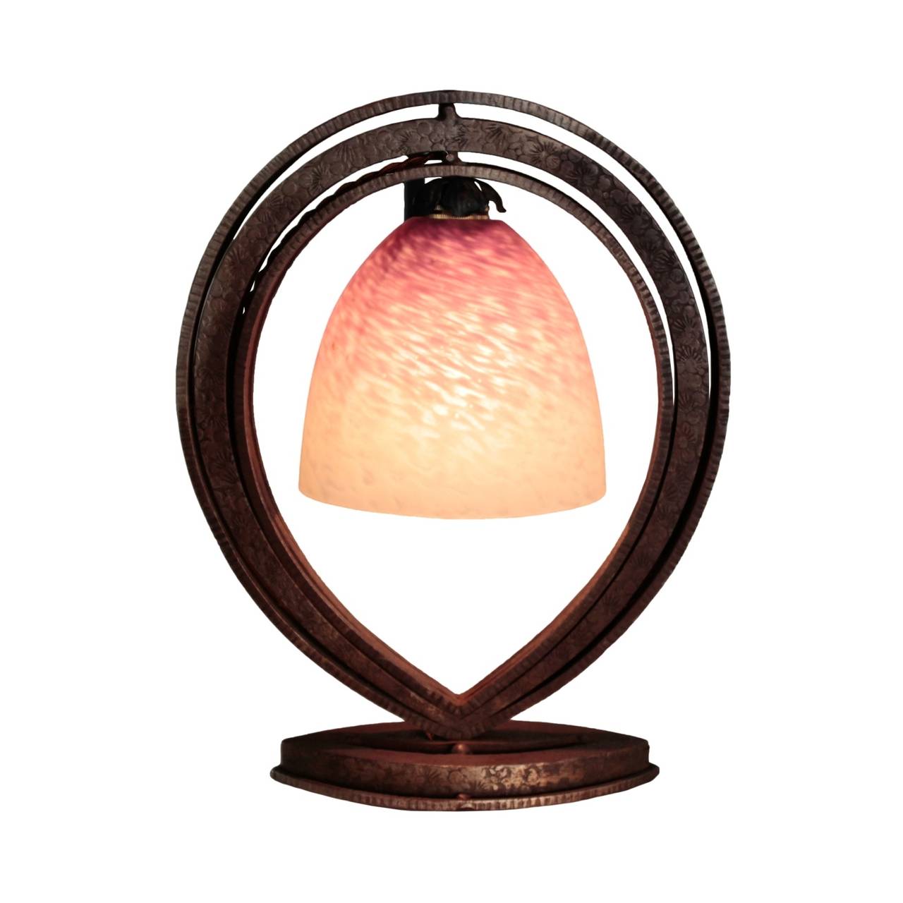 Mottled purple and white glass shade supported within a tri-layered fer forge (wrought iron) hoop with stamped flowers, on a stepped ellipsoid base with sharp points.
