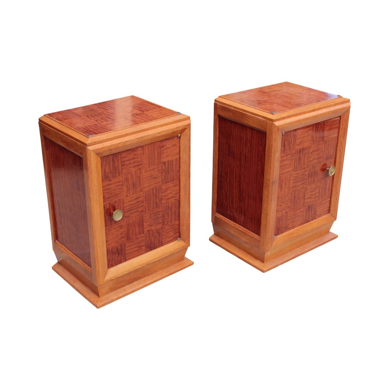 Pair of French Art Deco period nightstands of excellent quality, most likely designed by Louis Majorelle. Each with frame and platform base in oak; top, sides and door parquet veneered with African ribbon mahogany. Door fitted with original round