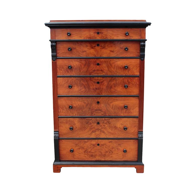 Architecturally designed seven-drawer chest in neoclassical/Napoleon III taste having a top with ebonized cornice and frieze drawer resting on a cabinet of six drawers in book-matched olive ash burl flanked by reeded pilasters and decorated with