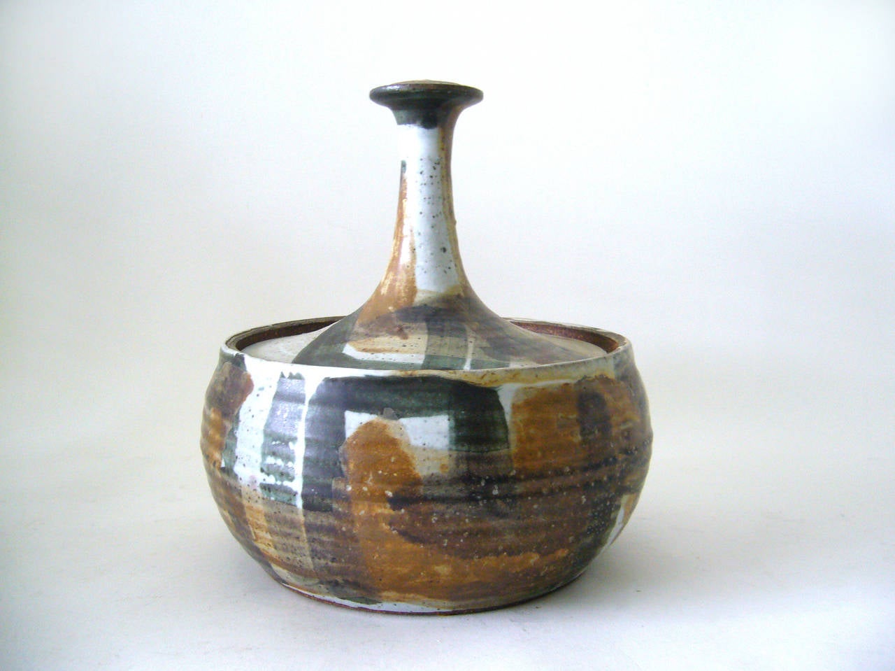 A stoneware lidded vessel created by Joel Edwards, circa 1950s or 1960s. Piece measures 9" in height by 8" in diameter. Signed Edwards on verso. In excellent vintage condition.