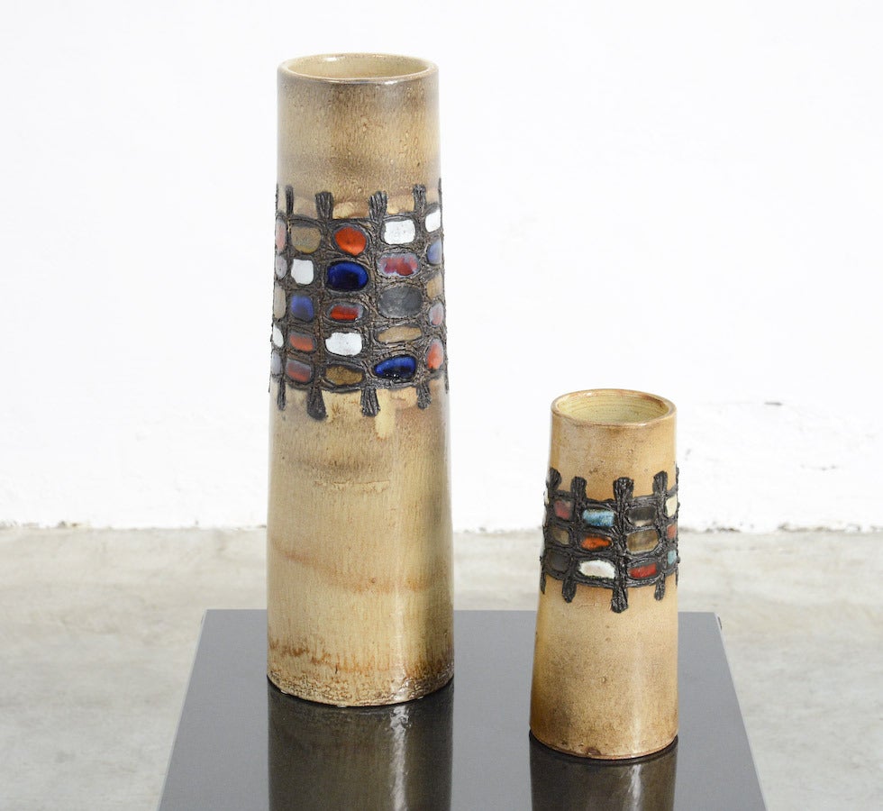 This nice set of 2 ceramic vases was made in the workshop of Perignem, Belgium around 1965.
The pure shape and the neutral matte main colour are in contrast with the shiny colourful geometric glaze details.
The vases are handthrow and so unique