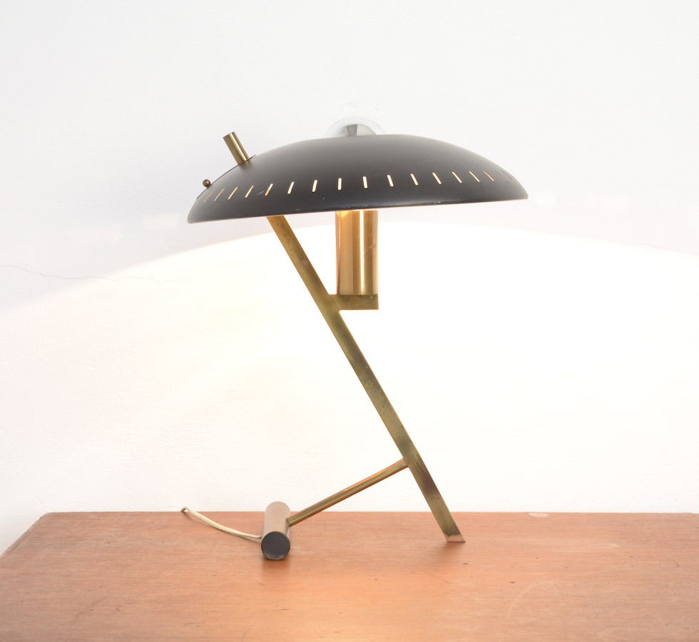 This beautiful desk lamp was designed by Louis Christiaan Kalff for Philips, Eindhoven in 1955.
It has a black curved perforated shade and a brass frame. This lamp is a first production. It is a rare and special piece. There are a few differences